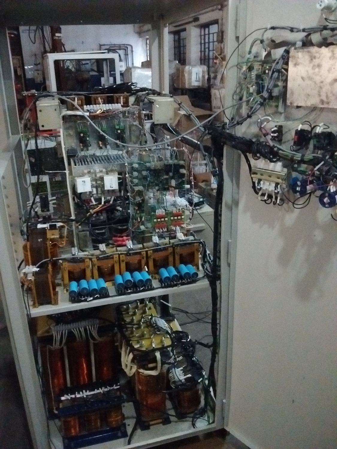 Open cabinet of a bidirectional inverter with control boards above and magnetics and capacitors below